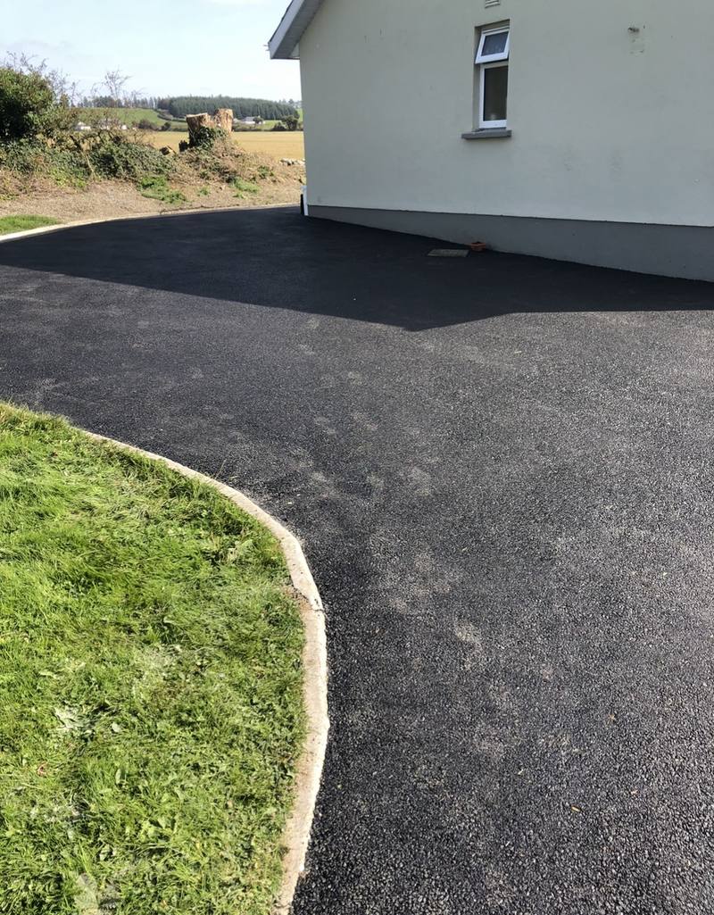 A tarmac driveway with a curved kerb to the lawn
