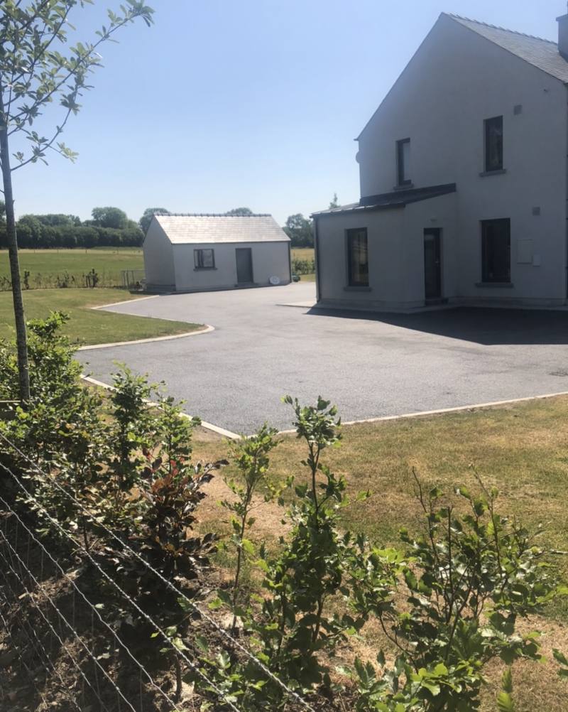 A tarmac yard around a house and shed in the country