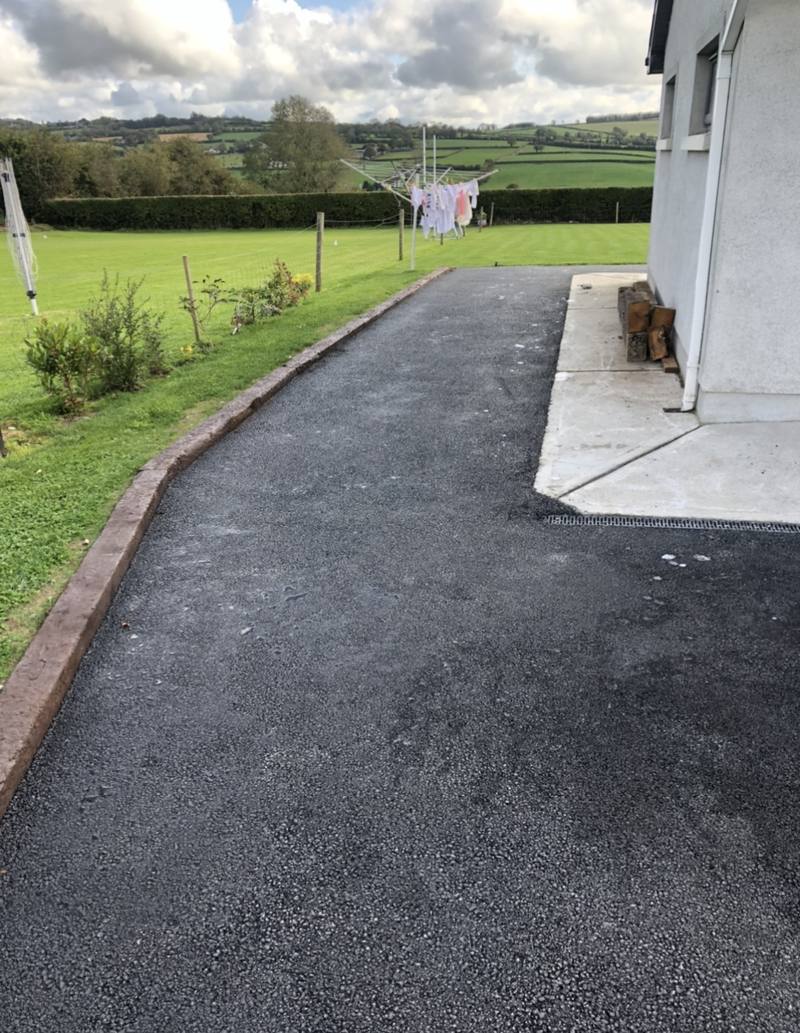 A tarmac drive along a house, edged with timber