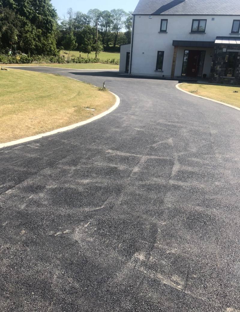 A tarmac driveway sweeping round a lawn to a new house