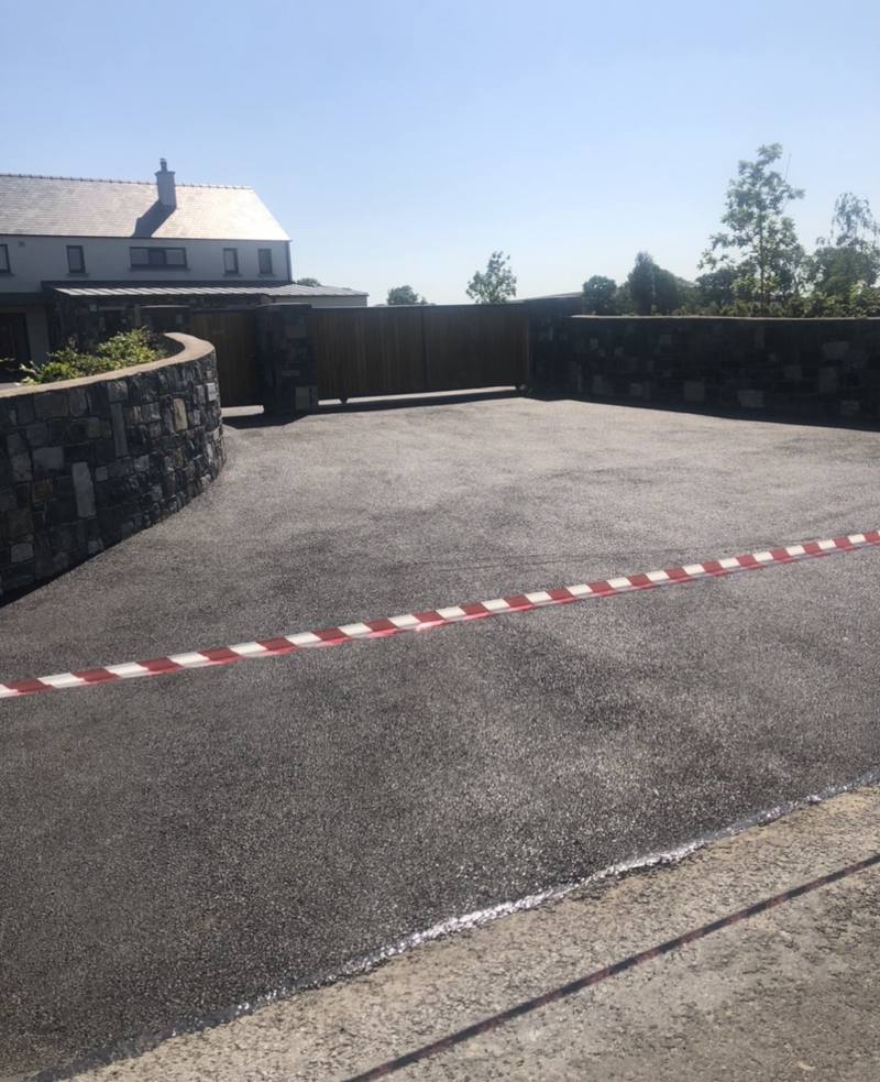 A tarmac yard inside a curved stone wall, taped off while it sets