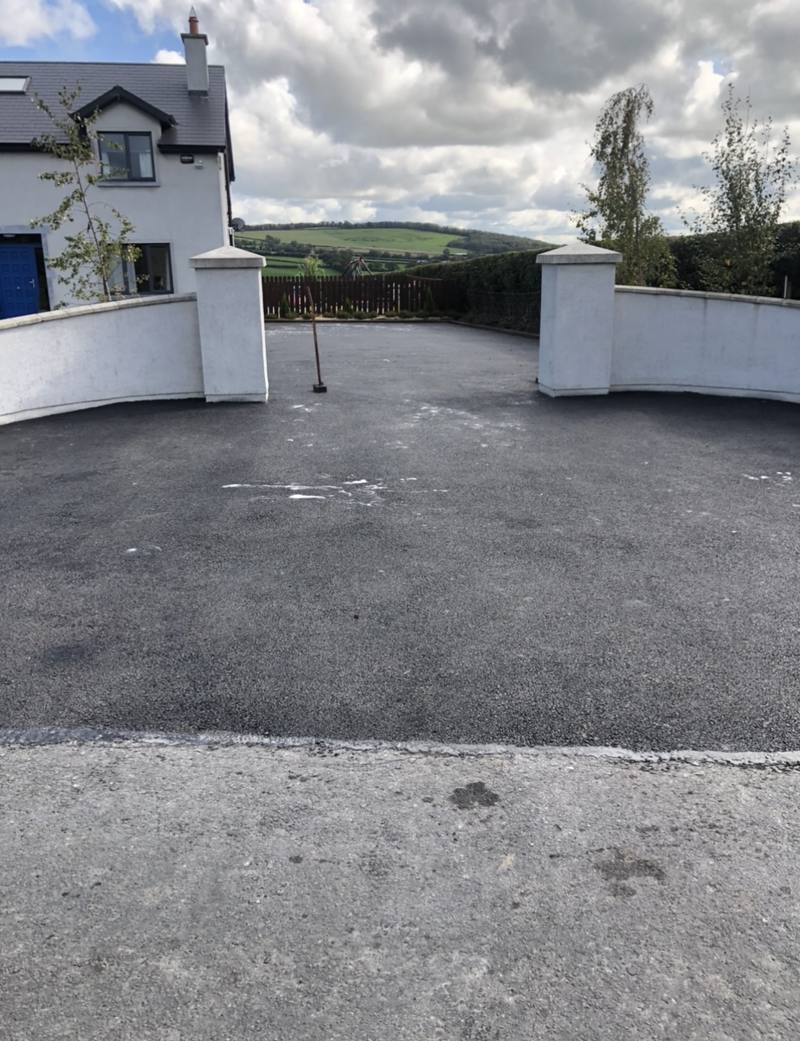 A tarmac entrance between white piers and walls