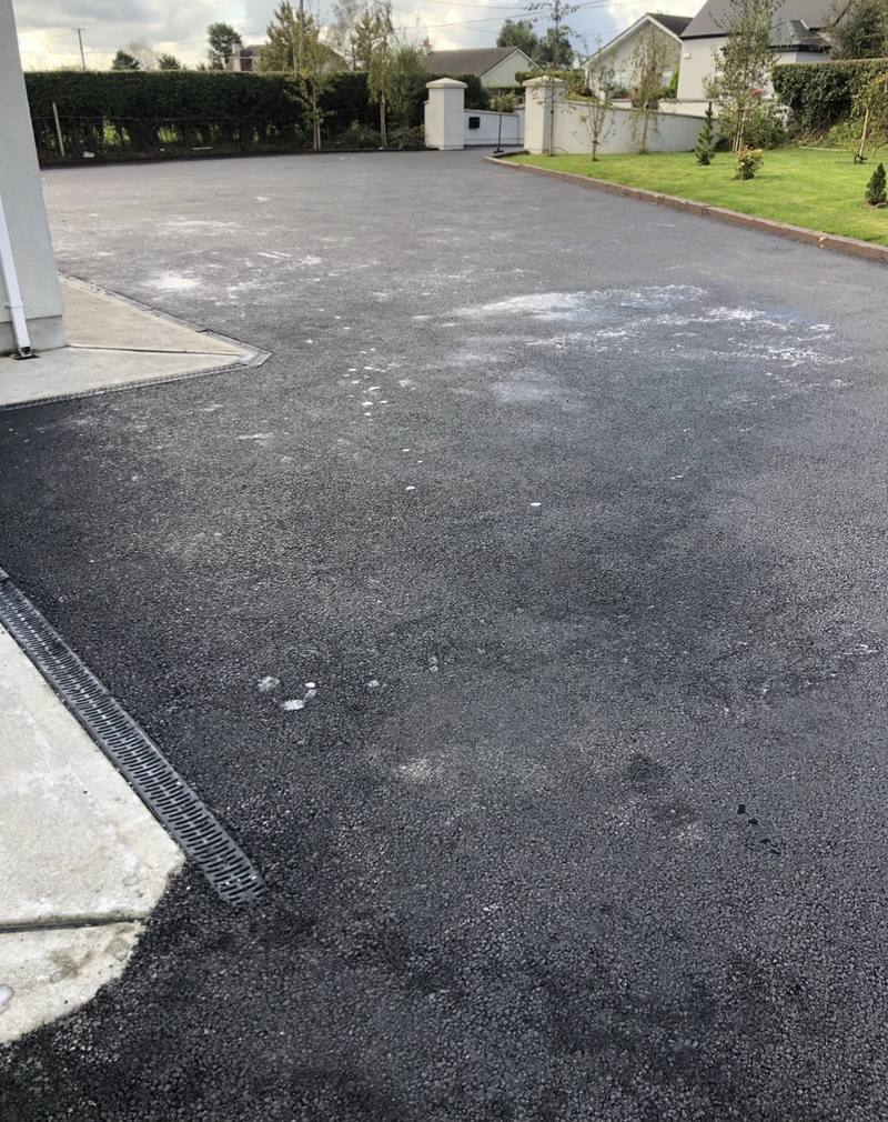 A tarmac yard with a channel drain across the back door